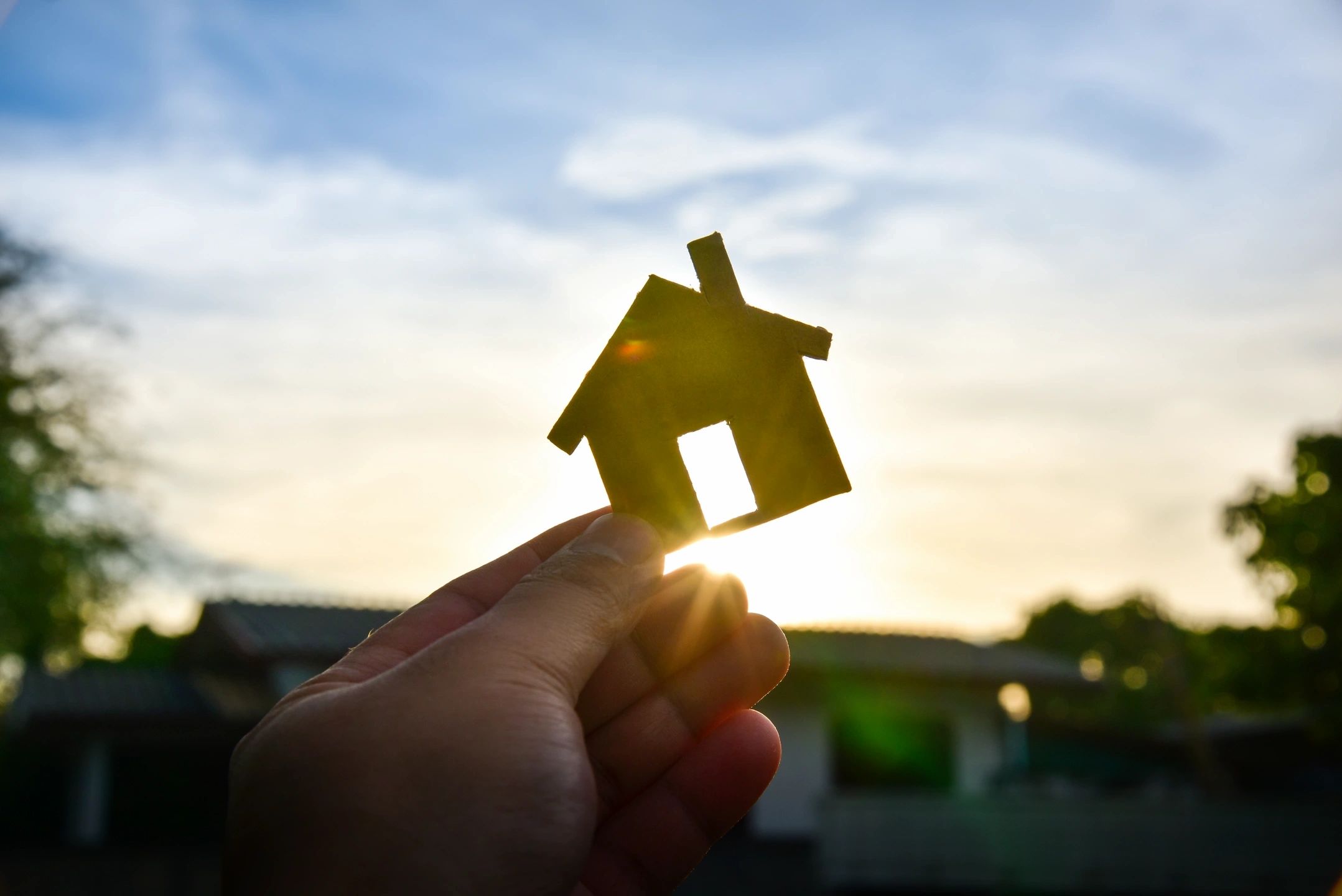 Silhouette of a home with the sun behind it